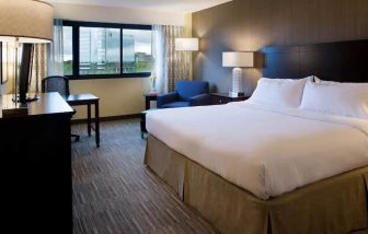 Spacious king size room with a king bed, chair. desk and view of city at the Hilton Nashville Airport.