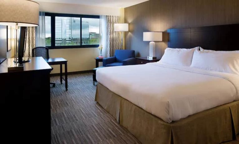 Spacious king size room with a king bed, chair. desk and view of city at the Hilton Nashville Airport.