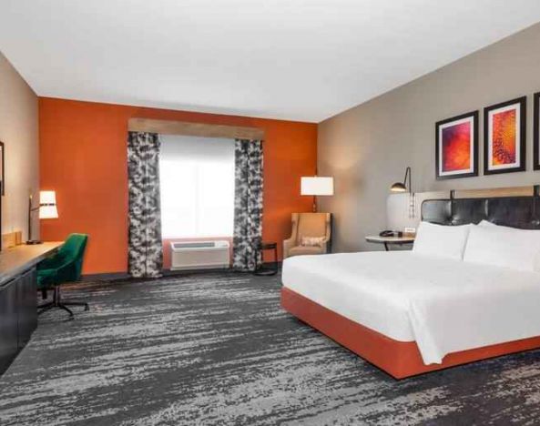 Spacious and comfortable king bedroom with window and TV screen at the Hilton Garden Inn Hays.