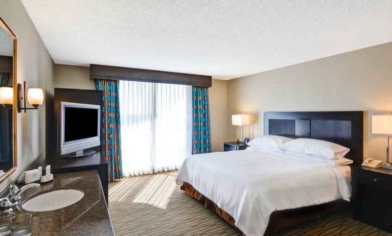 King bedroom with TV screen and window at the Embassy Suites by Hilton Miami - International Airport.