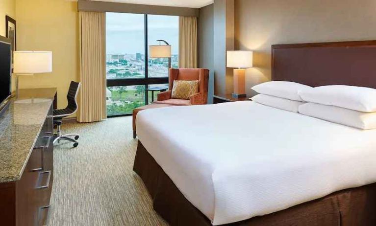 King size bed, desk and TV screen in a king guestroom at the Hilton San Antonio-Airport.