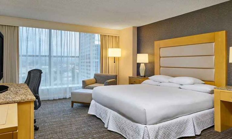 comfortable king-sized bedroom with work space and lounge area at Hilton Los Angeles North/Glendale & Executive Meeting Ctr.