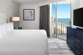 comfortable standard king room with TV and sea views at Embassy Suites by Hilton Myrtle Beach Oceanfront Resort.