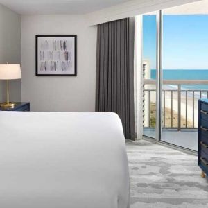 comfortable standard king room with TV and sea views at Embassy Suites by Hilton Myrtle Beach Oceanfront Resort.