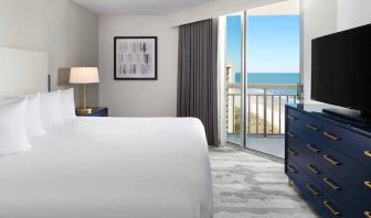 comfortable standard king room with TV and sea views at Embassy Suites by Hilton Myrtle Beach Oceanfront Resort.