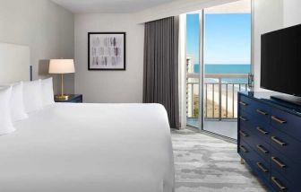 comfortable standard king room with TV and sea views at Embassy Suites by Hilton Myrtle Beach Oceanfront Resort.