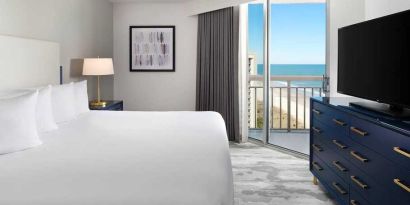 comfortable standard king room with TV and sea views at Embassy Suites by Hilton Myrtle Beach Oceanfront Resort.