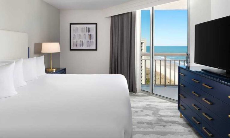 comfortable standard king room with TV and sea views at Embassy Suites by Hilton Myrtle Beach Oceanfront Resort.