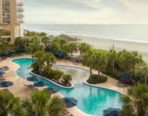 beautiful outdoor pool surrounded with greenery right by the beach at Hilton Myrtle Beach Resort.