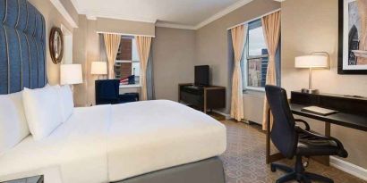 Delux king room with TV, work desk, and natural light at Hilton Milwaukee City Center.