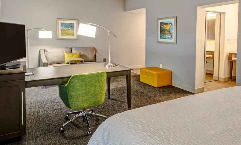 delux king room with TV, work desk, and lounge area at Hampton Inn & Suites San Jose Airport.