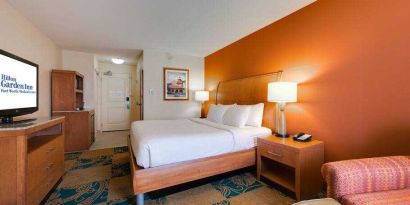 King size bed, TV screen and sofa in a king bedroom at the Hilton Garden Inn Fort Worth Medical Center.