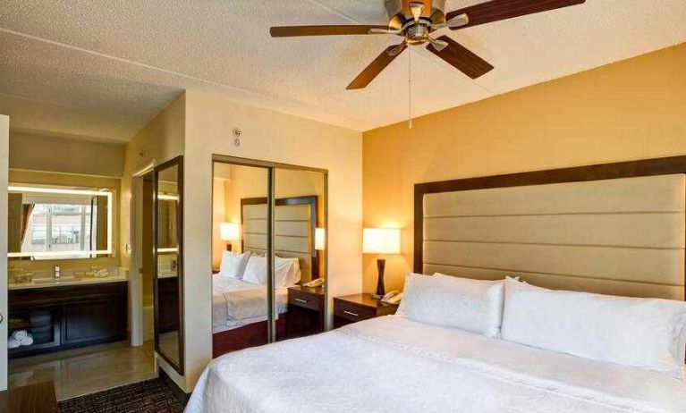 King size bed, fan and mirror in a king guestroom at the Homewood Suites by Hilton Washington, D.C. Downtown.