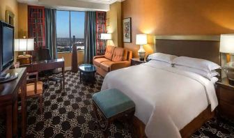 beautiful king room with natural light, TV, and work desk at Hilton Anatole.