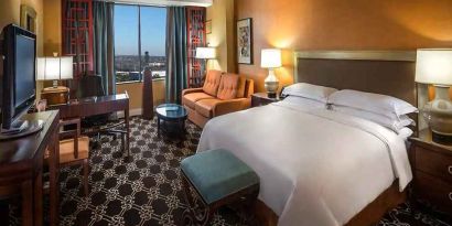 beautiful king room with natural light, TV, and work desk at Hilton Anatole.