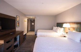 Double queen bedroom with TV screen at the Hampton Inn & Suites North Attleboro.