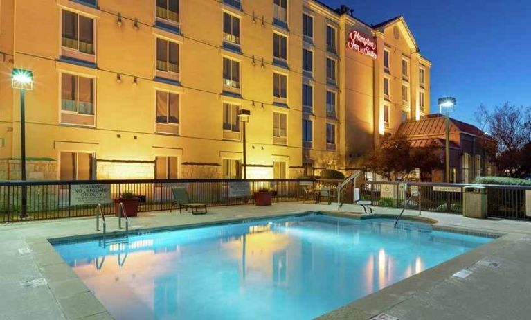 pretty outdoor pool with seating area and sun beds at Hampton Inn & Suites Austin-Airport.