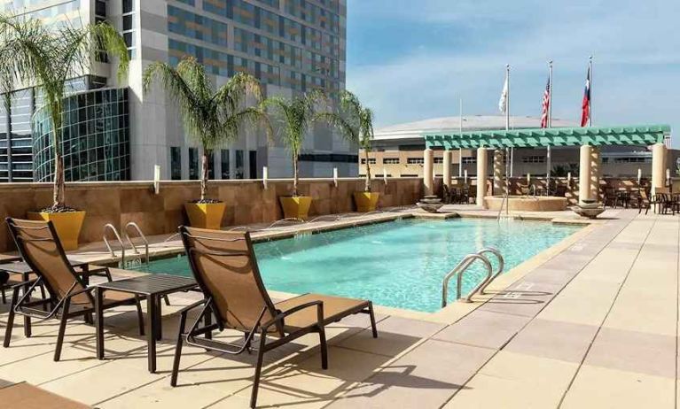 beautiful outdoor pool with sun beds and seating area at Embassy Suites by Hilton Houston Downtown.