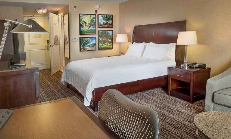 spacious king bedroom with TV, lounge area, and work desk ideal for working remotely at Hilton Garden Inn St. Louis Airport.