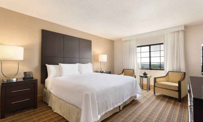 Comfortable king bedroom with window at the Embassy Suites by Hilton Greenville Golf Resort Conference Center