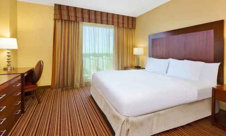 King size bed, window and desk in a king room at the Embassy Suites by Hilton Nashville SE Murfreesboro.