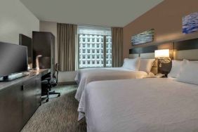 Two queen size beds, TV screen and desk in a hotel room at the Hilton Garden Inn Financial Center Manhattan Downtown, NY.