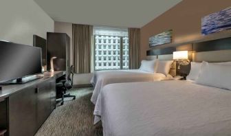 Two queen size beds, TV screen and desk in a hotel room at the Hilton Garden Inn Financial Center Manhattan Downtown, NY.