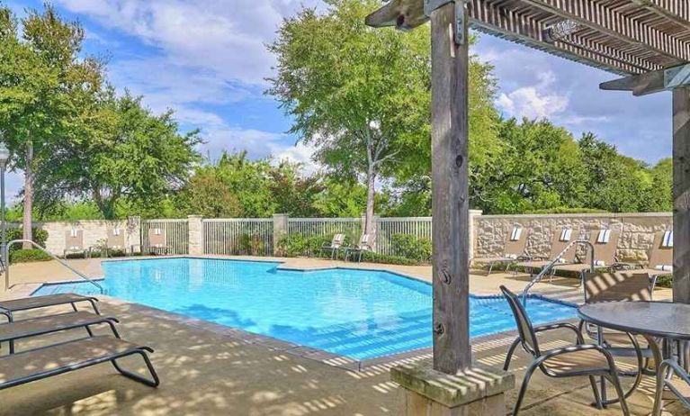 beautiful outdoor pool surrounded by greenery and with comfortable seating area at Hampton Inn & Suites Schertz.