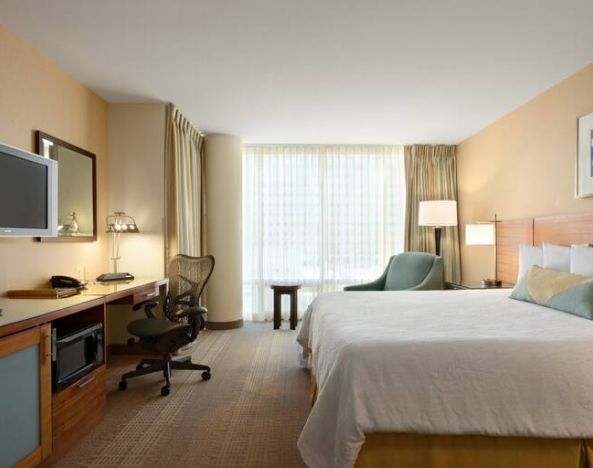 King guestroom with TV screen, desk and window at the Hilton Garden Inn Baltimore Inner Harbor.