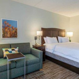 King size bed and sofa in a hotel room at the Hampton Inn Boston-Peabody.