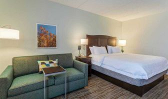 King size bed and sofa in a hotel room at the Hampton Inn Boston-Peabody.