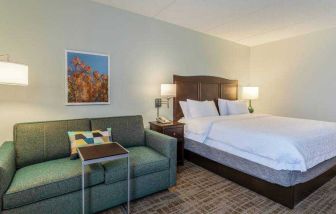 King size bed and sofa in a hotel room at the Hampton Inn Boston-Peabody.