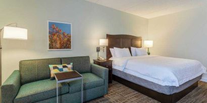 King size bed and sofa in a hotel room at the Hampton Inn Boston-Peabody.