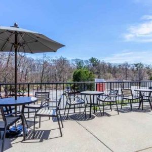 Outdoor patio with tables, chairs and sun umbrellas at the Hampton Inn Boston-Peabody.