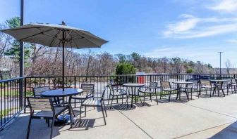 Outdoor patio with tables, chairs and sun umbrellas at the Hampton Inn Boston-Peabody.