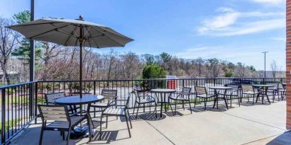 Outdoor patio with tables, chairs and sun umbrellas at the Hampton Inn Boston-Peabody.