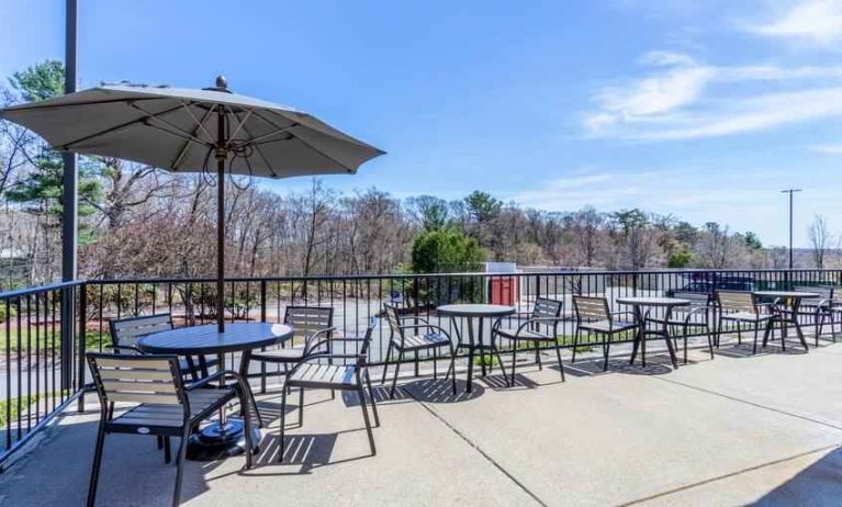 Outdoor patio with tables, chairs and sun umbrellas at the Hampton Inn Boston-Peabody.