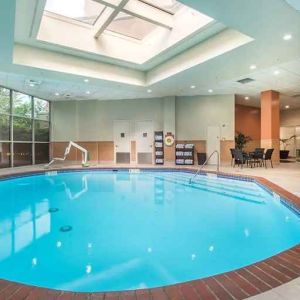 bright-lit indoor pool with sun rooff and comfortable seating area at Embassy Suites by Hilton Seattle Tacoma International Airport.