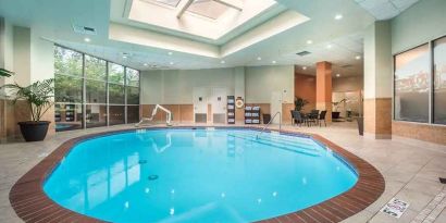 bright-lit indoor pool with sun rooff and comfortable seating area at Embassy Suites by Hilton Seattle Tacoma International Airport.