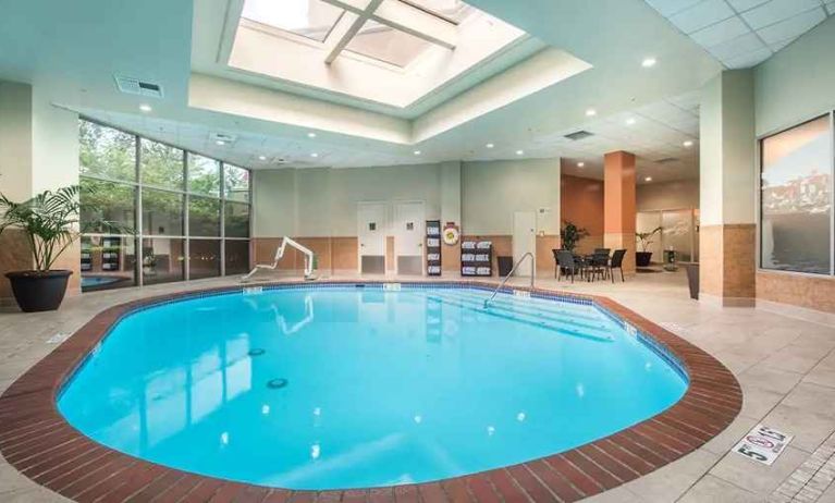 bright-lit indoor pool with sun rooff and comfortable seating area at Embassy Suites by Hilton Seattle Tacoma International Airport.