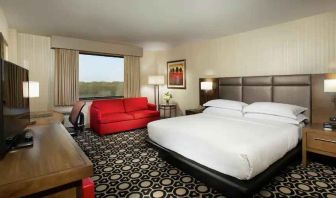 King suite with sofa, TV screen and window at the Hilton Chicago-Northbrook.