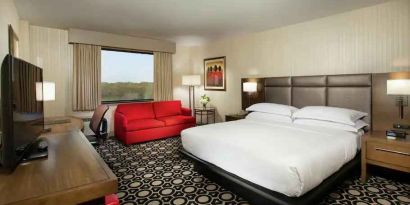 King suite with sofa, TV screen and window at the Hilton Chicago-Northbrook.