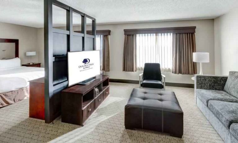 Spacious king suite with TV screen and sofa at the DoubleTree by Hilton Wichita Airport.