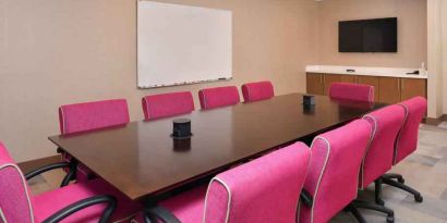 Small meeting room with pink chairs at the Hampton Inn & Suites St. Paul Oakdale/Woodbury by Hilton.