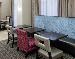 Hotel workspace with tables and chairs at the Hampton Inn & Suites Westford-Chelmsford.