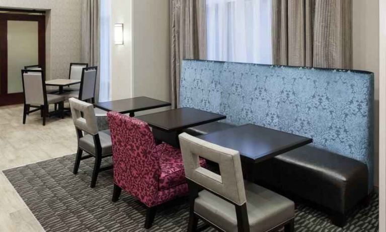 Hotel workspace with tables and chairs at the Hampton Inn & Suites Westford-Chelmsford.