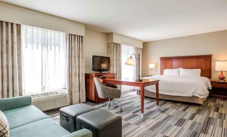 Spacious king suite with desk and sofa at the Hampton Inn & Suites Westford-Chelmsford.