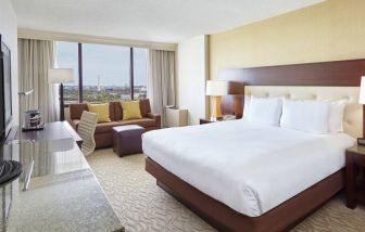 Bright king bedroom with sofa, window and desk at the DoubleTree by Hilton Washington DC - Crystal City.