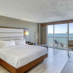 King size bed, TV screen and window in a hotel room at the DoubleTree Beach Resort by Hilton Tampa Bay - North Redingto.