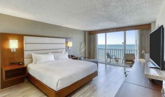 King size bed, TV screen and window in a hotel room at the DoubleTree Beach Resort by Hilton Tampa Bay - North Redingto.